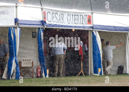 La folla si ripara dalla pioggia a un gioco equo Foto Stock