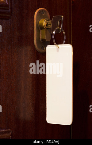 La chiave in una serratura dotata di una schermata bianca vuota portachiavi con copyspace Foto Stock