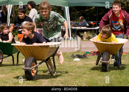 I bambini che partecipano in carriola gara a Oakhanger Village Show, Hampshire REGNO UNITO. Foto Stock