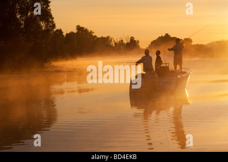 Tre uomini in una barca da pesca in una nebbiosa alba. Acqua gialla, Kakadu National Park, Australia Foto Stock