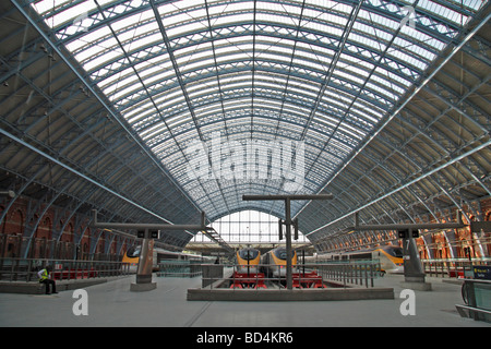 Un passeggero seduto sotto l'arco principale al terminal principale dell'dalla stazione ferroviaria internazionale di St Pancras, London, Regno Unito. Foto Stock