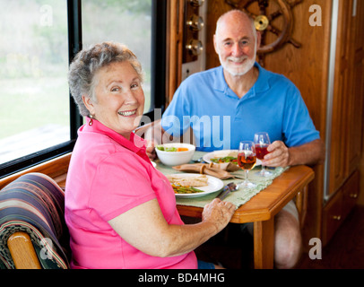 Coppia senior gode di una sana il pranzo nella cucina della loro casa a motore messa a fuoco sulla moglie Foto Stock