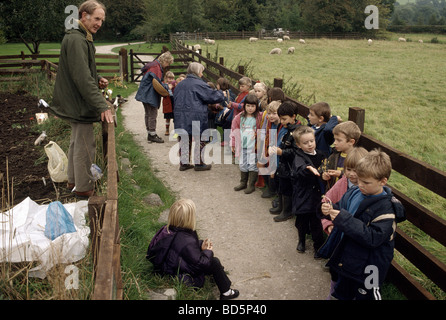 I bambini della scuola elementare in visita a una fattoria di grano nel Derbyshire dove essi sono mostrati come coltivare frumento in un vecchio modo Foto Stock