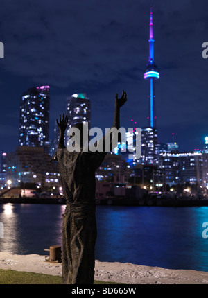 La scultura di un uomo rivolto verso la CN Tower con le mani alzate Foto Stock