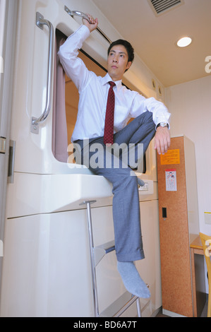 Uomo seduto in capsula hotel Foto Stock
