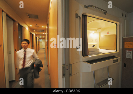 Imprenditore a piedi nella capsula hotel Foto Stock