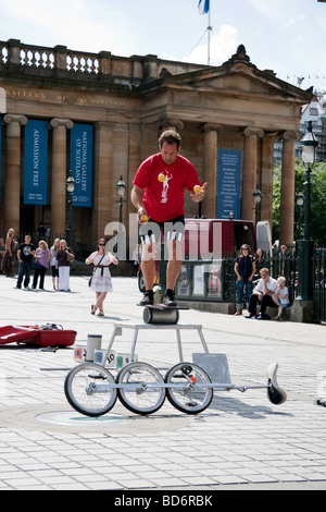 Un esecutore di strada giocoleria e bilanciamento durante un atto al di fuori della galleria su Edimburgo di Tumulo durante il Fringe Festival Foto Stock