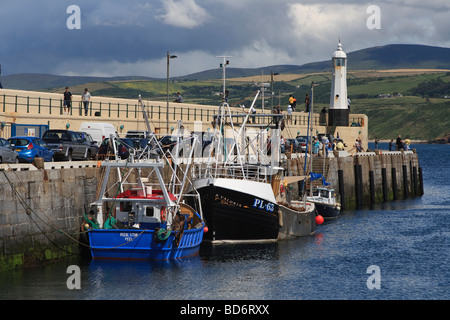 Il frangiflutti in Peel, Isola di Man, con un numero di barche da pesca ormeggiate e persone di pesca Foto Stock