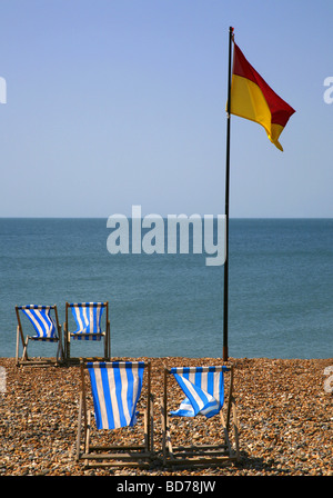 Una balneazione sicura bandiera e sedie a sdraio a Brighton, Sussex. Foto Stock