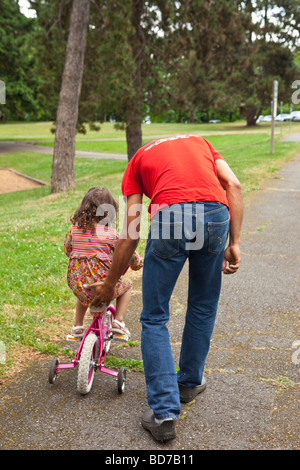 Padre aiutando la figlia in bicicletta Foto Stock