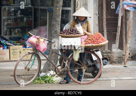 Una donna per la vendita di frutta da una bicicletta in Vietnam a Hanoi Foto Stock