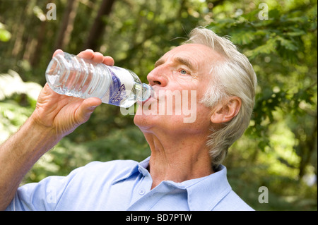 Uomo maturo di bere acqua minerale in bottiglia Foto Stock