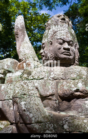 Un custode di pietra alla fine di un ponte sopra il massiccio che racchiude fossato nei pressi di Angkor Thom Foto Stock