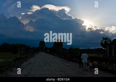 La sera tardi la vista giù per la strada rialzata che conduce a Angkor Wat con un sunburst proveniente da dietro un banco di nuvole Foto Stock