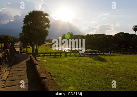 La sera tardi la vista giù per la strada rialzata che conduce a Angkor Wat con un sunburst proveniente da dietro un banco di nuvole Foto Stock