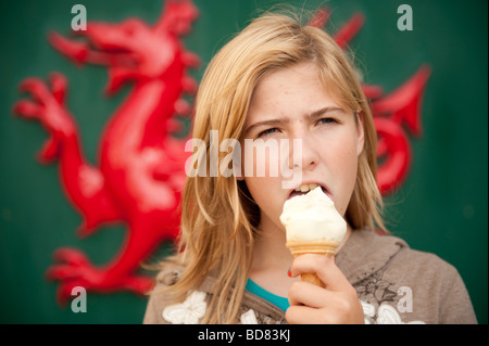 Giovane ragazza adolescente di mangiare gelato welsh drago rosso in background Foto Stock