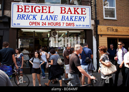 Persone di mangiare al di fuori del famoso Bagel cuocere pasticceria a Brick Lane domenica giorno di mercato. Questo è il più famoso bagel shop a Londra. Foto Stock