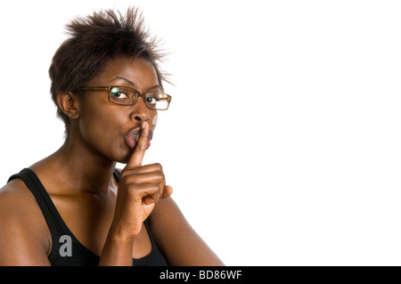 Chiudere orizzontale fino studio ritratto di un attraente donna africana con il suo dito indice fino alla sua labbra in un gesto shoosh Foto Stock