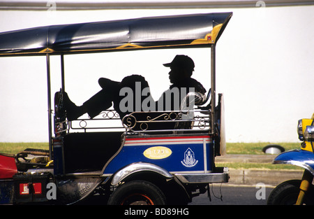 Uomo appoggiato a un rickshaw Foto Stock