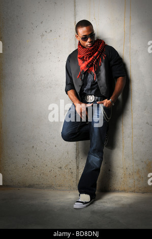 African American uomo con sciarpa rossa in piedi contro un muro di cemento Foto Stock