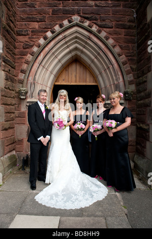 La sposa per suo padre e sua bridesmaids all'esterno della chiesa Foto Stock