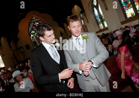 Lo sposo e il miglior uomo controllare il tempo all'interno della chiesa Foto Stock