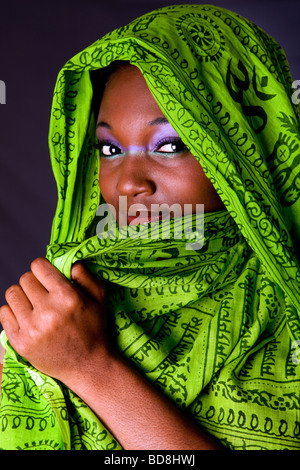 La faccia di un timido innocenzo bella giovane africano donna americana che copre la bocca con headwrap verde Foto Stock