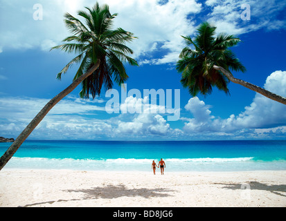 Paio di attraversamento di spiaggia di sabbia bianca tenendo le mani ad Anse Intendance beach sull'Isola di Mahe in Seychelles Foto Stock