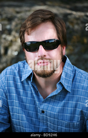 Uomo con occhiali da sole scuri guarda con fiducia al visualizzatore Foto Stock