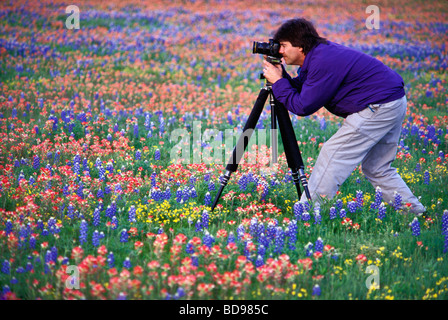 Fotografo guardando attraverso il mirino della fotocamera su treppiede nel Paese delle Colline del Texas Foto Stock