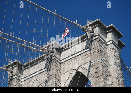 Close up della bandiera americana volare al di sopra del west Pilone del ponte di Brooklyn, Dumbo, Brooklyn, New York. Foto Stock