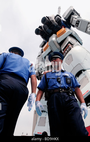 Poliziotti di stare accanto alla replica di gigante di fantascienza animazione robot Gundam in Seaside Park in Odaiba grande isola artificiale nella Baia di Tokyo, Giappone Foto Stock