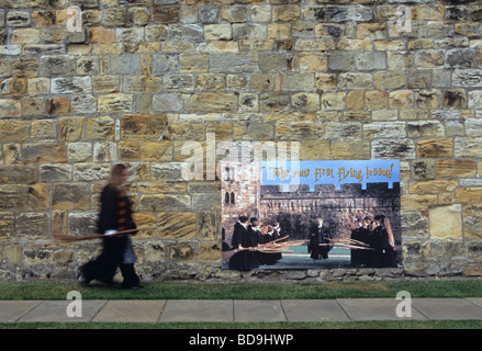 Una guida femmina vestita come Harry Potter cammina davanti ad una parete in Alnwick Castle in primo piano nel film Foto Stock