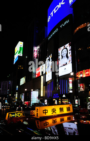 Taxi segno pubblicità con schermi in background nel quartiere di Ginza Tokyo Giappone Foto Stock