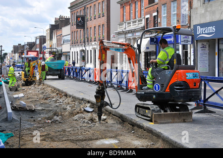 Scena a Brentwood shopping di lavoro di strada e lavori stradali mini-digger idraulico di lavoro per il conducente della macchina dotato di martello demolitore Inghilterra Regno Unito Foto Stock