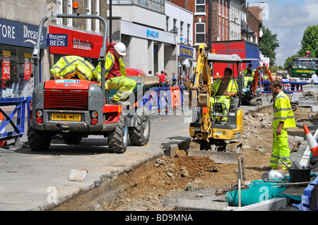 Lo shopping di Brentwood high street aggiornamento strade e pavimentazioni con mini escavatore e autocarro Foto Stock