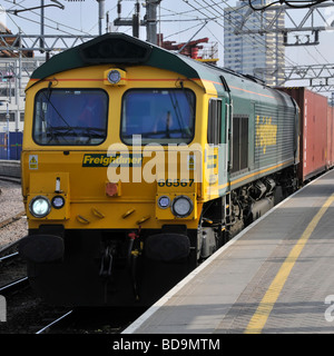 Stratford East London Freightliner locomotore 66567 con un contenitore di treni merci piattaforma passante Foto Stock