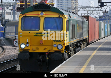 Vista frontale conducente cabina Locomotive Freightliner 66567 con un trasporto container treno merci passando piattaforma Stratford East London Newham Inghilterra Regno Unito Foto Stock