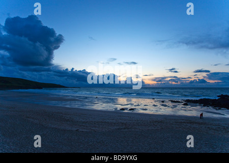 Giovane camminando lungo la spiaggia Porthmeor dopo il tramonto in estate St Ives Cornwall Inghilterra UK Regno Unito GB Gran Bretagna British Foto Stock
