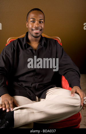 Fiducioso uomo nero in poltrona Foto Stock