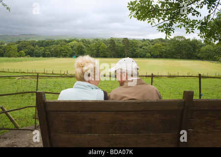 Coppia di anziani seduti sulla panchina in chat e godendo della vista Kirby Lonsdale Lake District Cumbria Inghilterra England Foto Stock