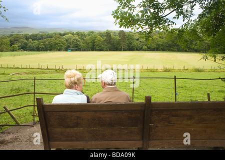 Coppia di anziani seduti sulla panchina in chat e godendo della vista Kirby Lonsdale Lake District Cumbria Inghilterra England Foto Stock