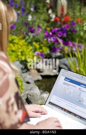 Donna con notebook che mostra il social networking Facebook schermata splash page Foto Stock