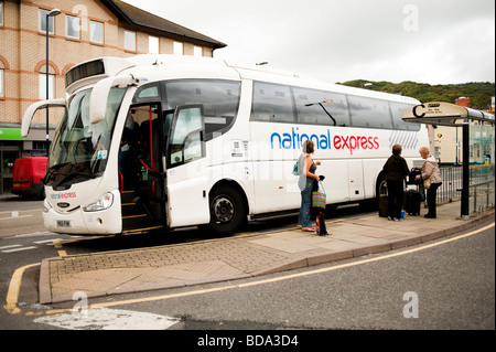 I passeggeri che emergono da un National Express a lunga distanza autobus ad una fermata del bus Foto Stock