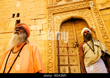 Basso angolo vista di due sadhus in piedi di fronte ad un edificio Jaisalmer Rajasthan in India Foto Stock