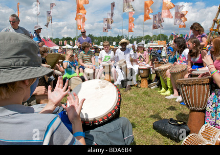 Famiglie e bambini godendo di un drumming workshop al Womad Festival di musica con bandiere e la folla Foto Stock