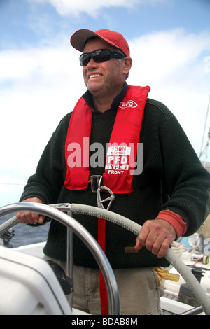 Il timoniere su un moderno yacht di indossare un giubbotto di salvataggio e il cablaggio Foto Stock