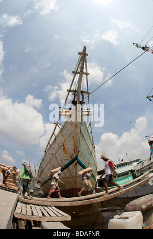 Java Indonesia Jakarta Sunda Kelapa lavoratori caricamento a vela in legno imbarcazione cargo su gangplank Foto Stock