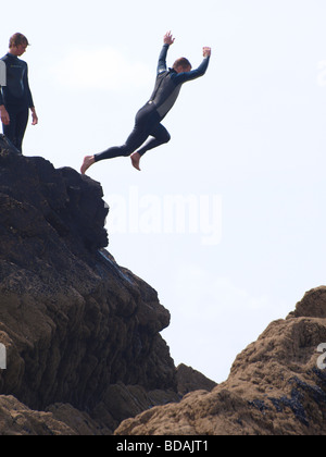 Gli adolescenti jumping Rocks off in un mare piscina, Bude, Cornwall Foto Stock