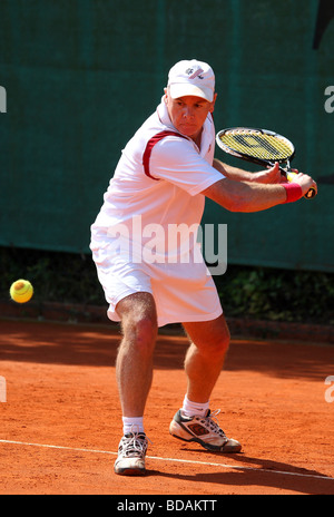 Uomo anziano Giocare il rovescio in un torneo di tennis Foto Stock